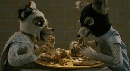 Still from The Fantastic Mr. Fox showing two stop-motion foxes hunched over a plate of breakfast food, tearing into it savagely